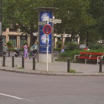 On a park bench next to the street