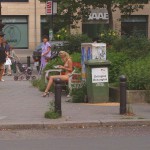 On a park bench next to the street
